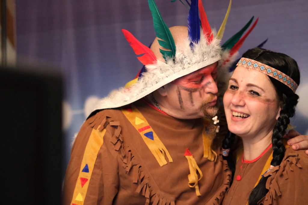 Pár v kostýmoch indiánov sa fotí vo fotobúdke na maškarnom plese vo Vrádišti, indián dáva indiánke bozk.